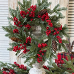 Christmas wreath with red berries and pine cones on a decorative stand.